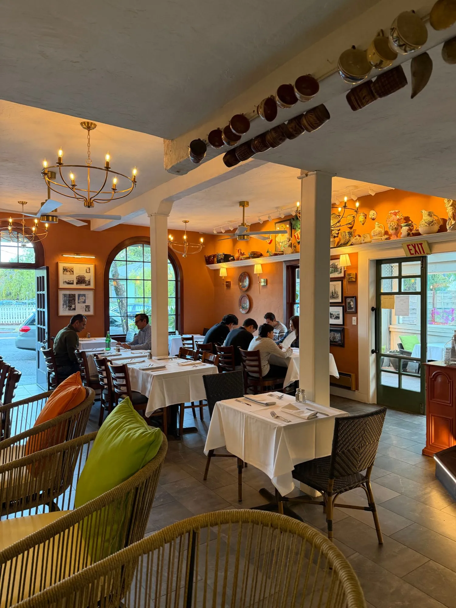 Guests dining in the orange-walled front dining room under brass chandeliers