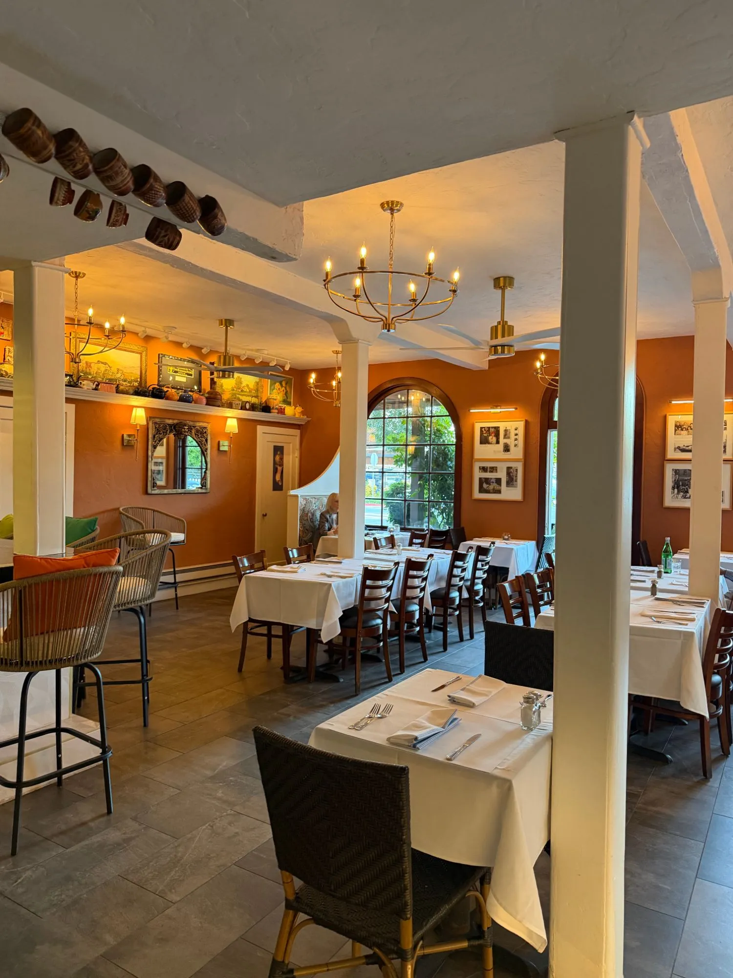 The dining room set for dinner, with arched windows and the family photographs on the walls
